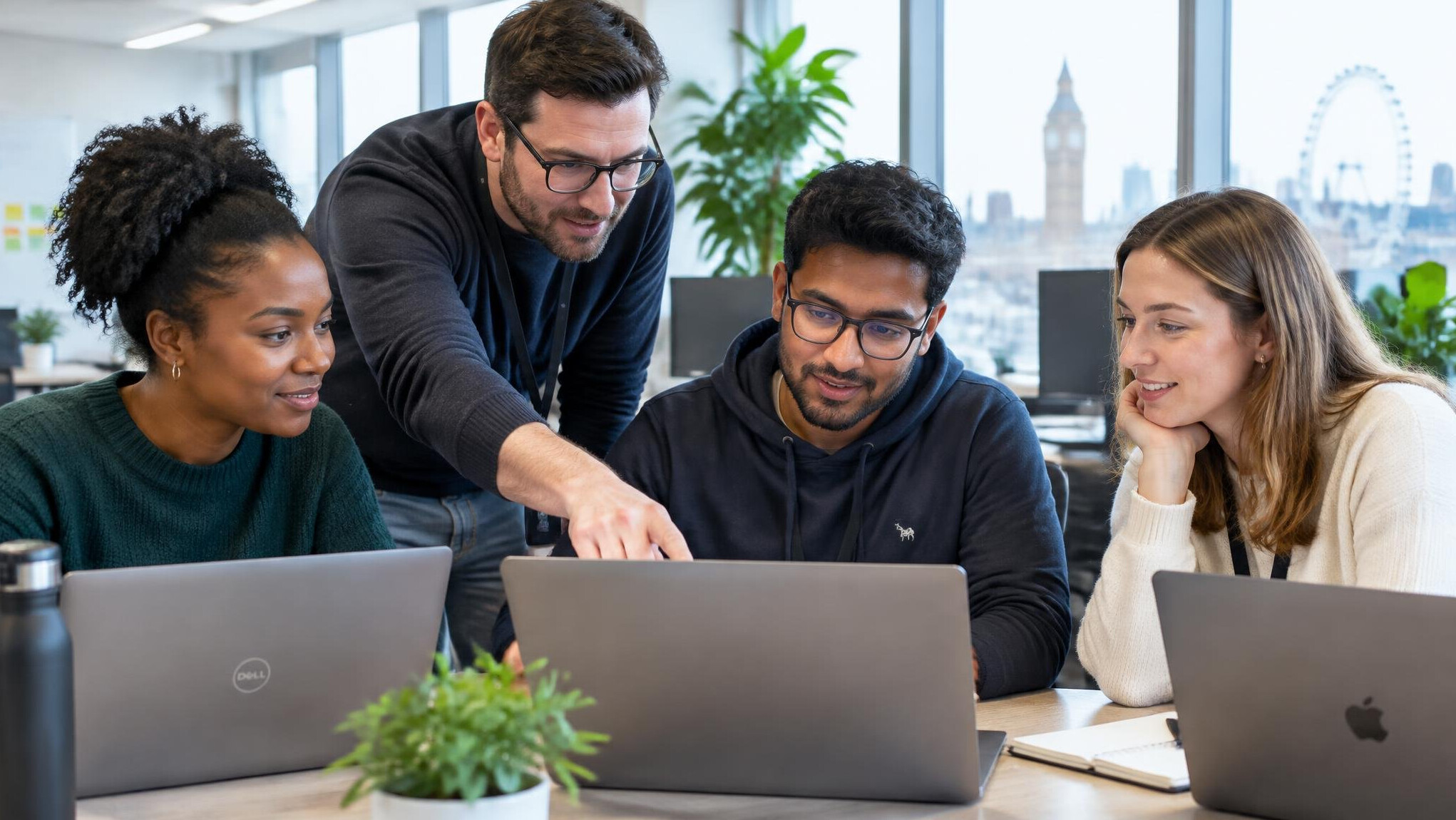 Team of developers working together at laptops in a modern office